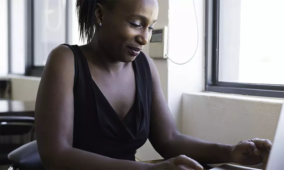 Woman smiles as she works on building an online profile at her desk