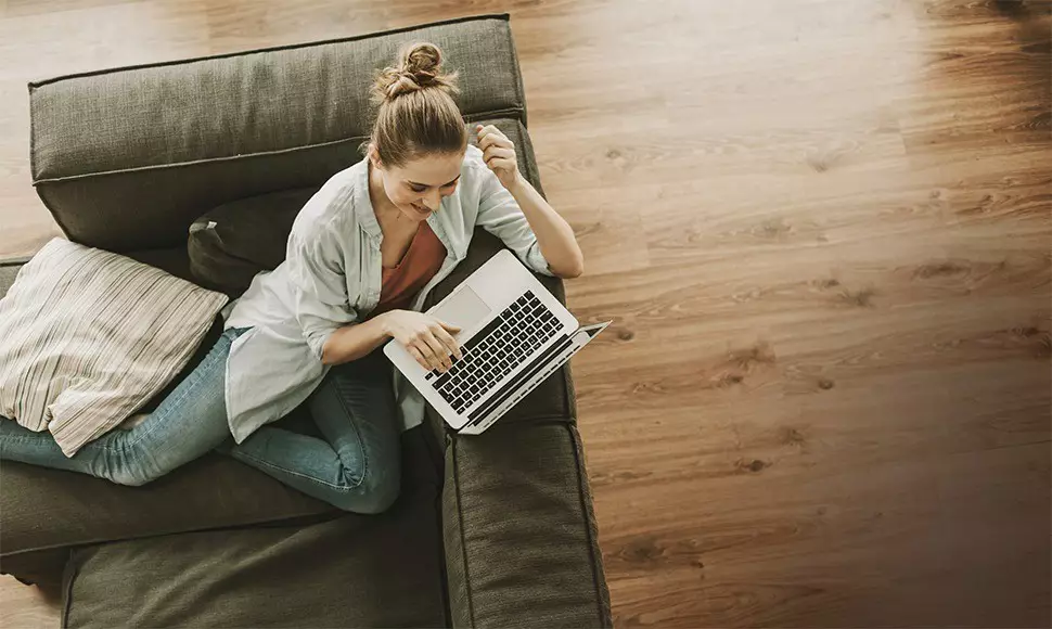 Aerial view of a woman looking for jobs on her laptop while she sits in her living room