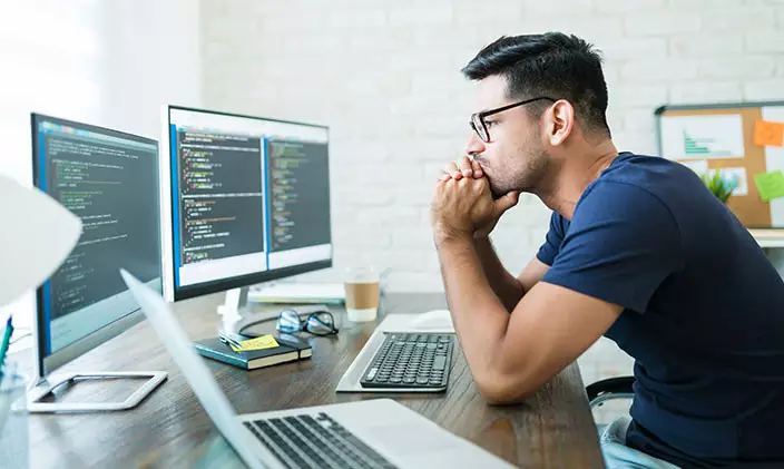 IT professional looking thoughtful into computer screen