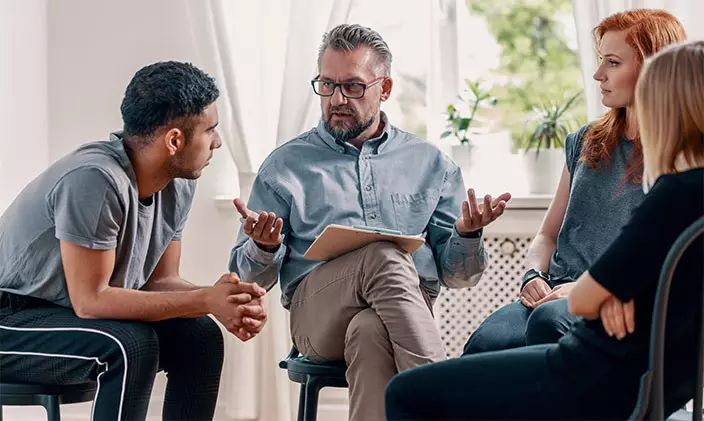 Male juvenile corrections officer speaking to a group of young adults