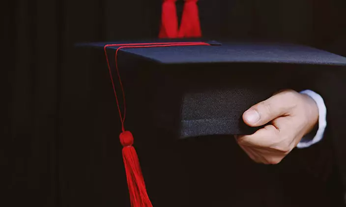 Male graduate holding a graduation cap to represent Marco Grijalva graduating from University of Phoenix.