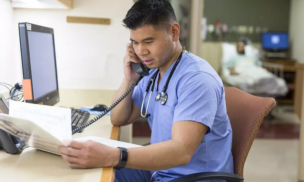 A nurse leader examines a patient's chart and makes a call