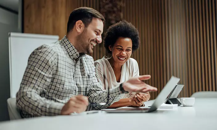 Mentor and mentee share a chuckle in a boardroom