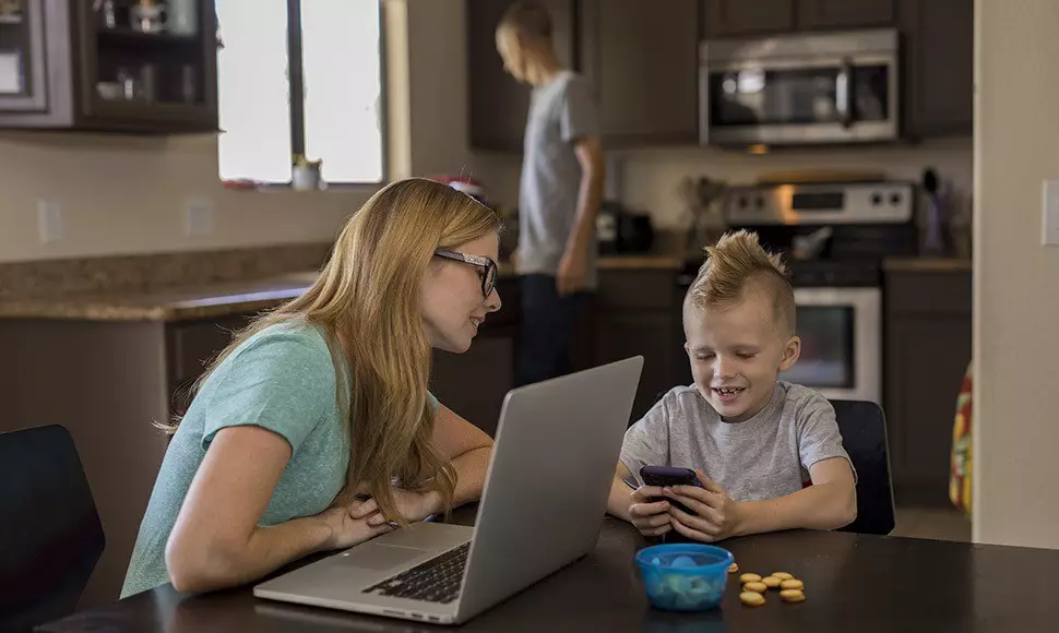 Parent with children studying in kitchen