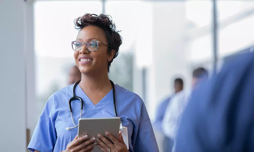 Nurse practitioner smiling, holding a clipboard