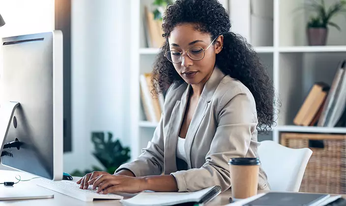 Legal Services employee working on a case at computer with coffee