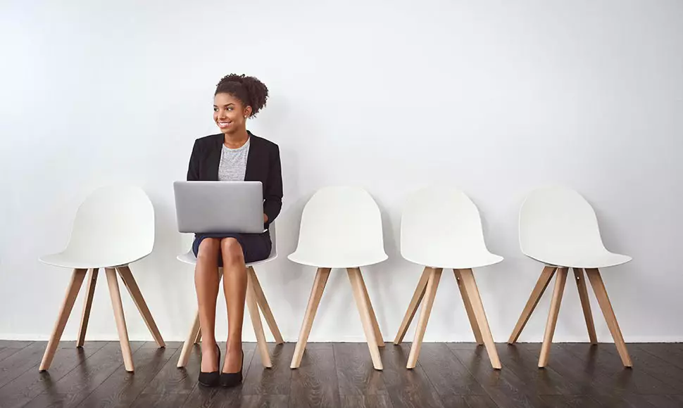 Female professional sitting in a waiting room on her laptop