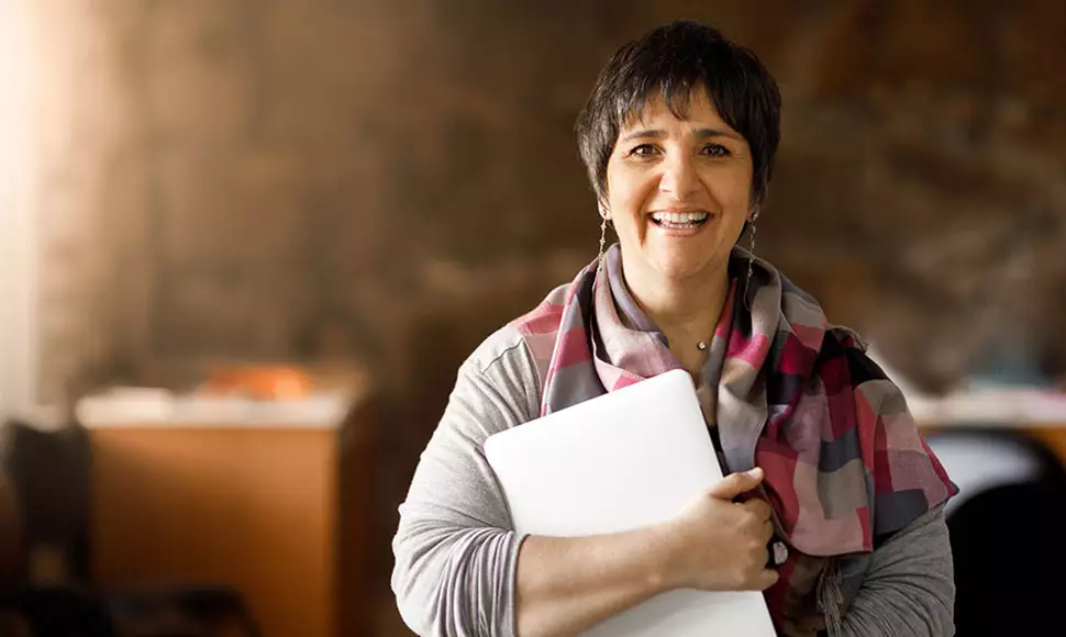 Female public administrator holding closed laptop and smiling