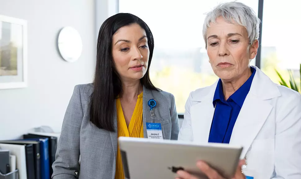 A nurse going over information with another female employee