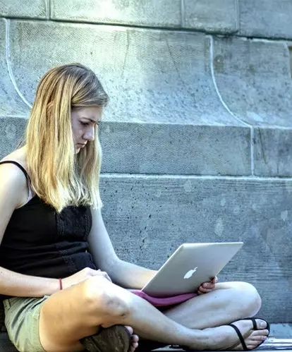 A university of phoenix student sitting on the ground, researching smart borrowing on their laptop