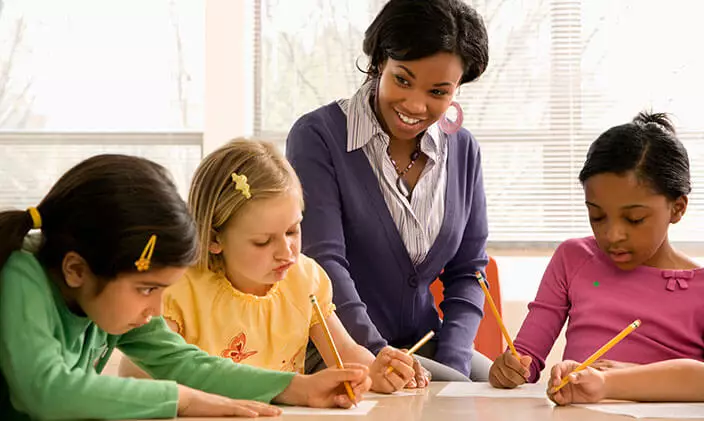 Black female teacher, smiling and helping students