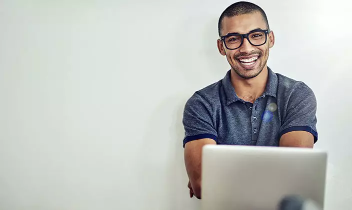Smiling online student wearing glasses and with laptop