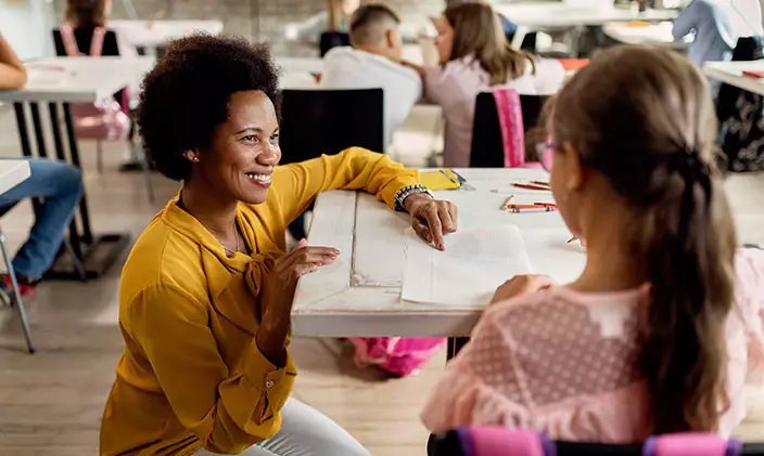 Female K-12 teacher talking to a student in the classroom