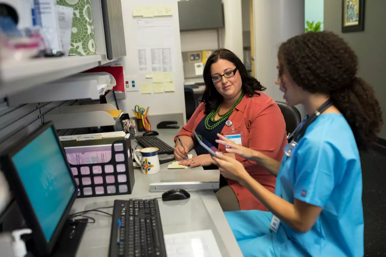 Two health admin professionals work together in a doctor's office