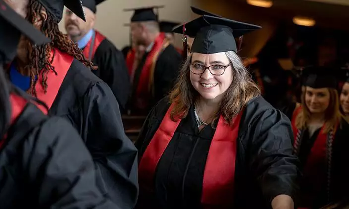 Student smiling among others wearing caps and gowns