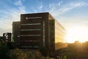 Link to an image of the ¼ϲʿ building with a setting sun in the background, turning the window gold