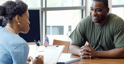 Woman sitting across from male student, both smiling