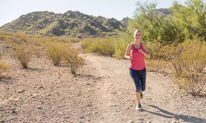 Woman running along nature trail