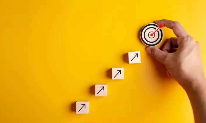 Four wooden blocks with arrows on them pointing to a round wooden target to signify performance management