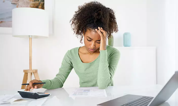 African American woman frustrated with finances, seeing if she's eligible for financial aid.
