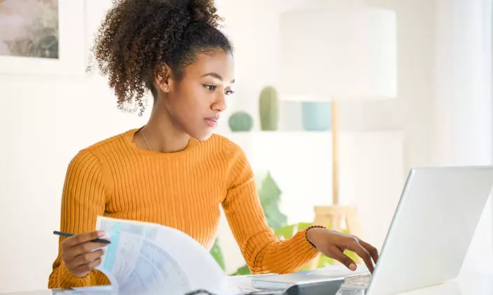 Young african american woman taking online classes on laptop