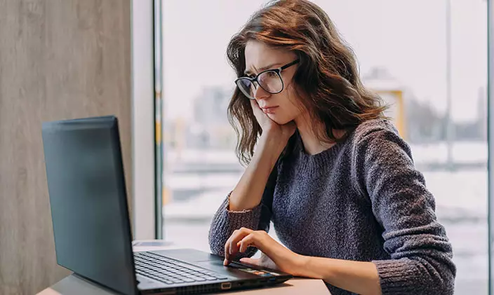 Female professional looks disgruntled while working on a laptop