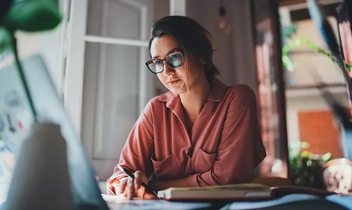 Woman in glasses overlooking laptop