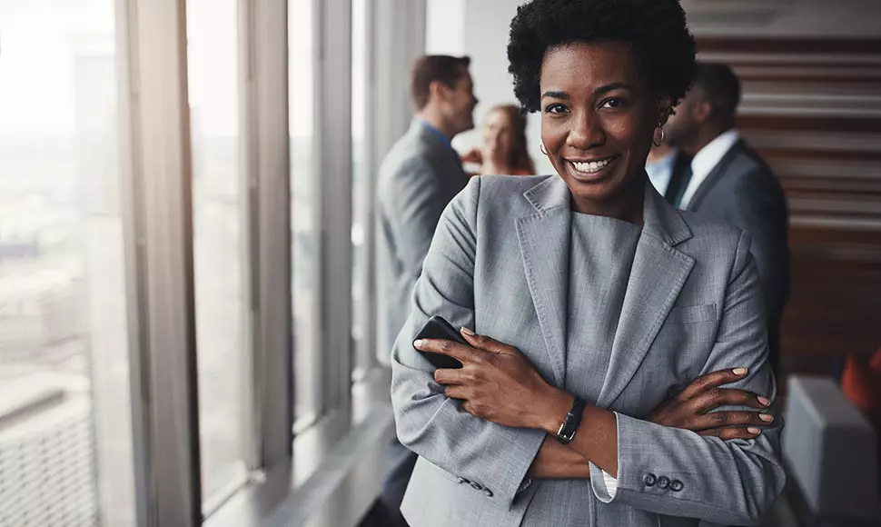 Black female professional smiles next to the window from her high-rise office