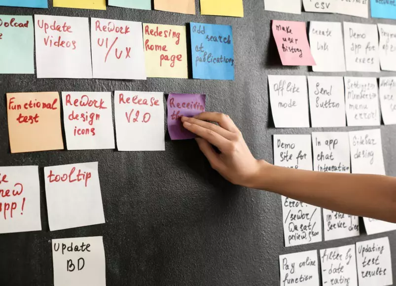 A scrum master plans the upcoming sprint with sticky notes on a wall