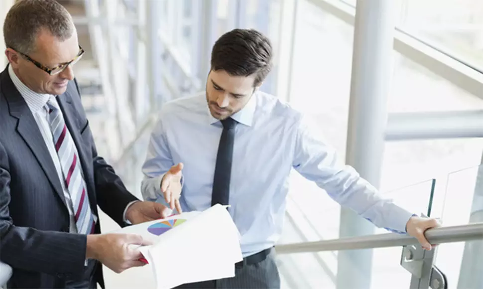 Two business man discussing business, looking over papers